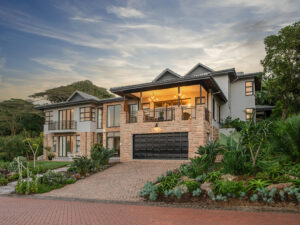 Exterior view of Sea Breeze Villa showing its contemporary architecture, stone accents, landscaped gardens and paved driveway.